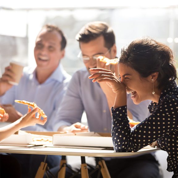 Group of young professionals eating pizza and laughing