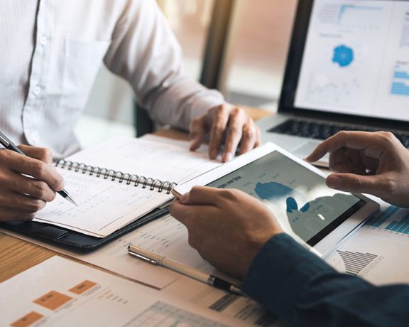 A close up of two people's hands writing in notebooks