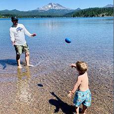 Photo of person playing with child in a lake